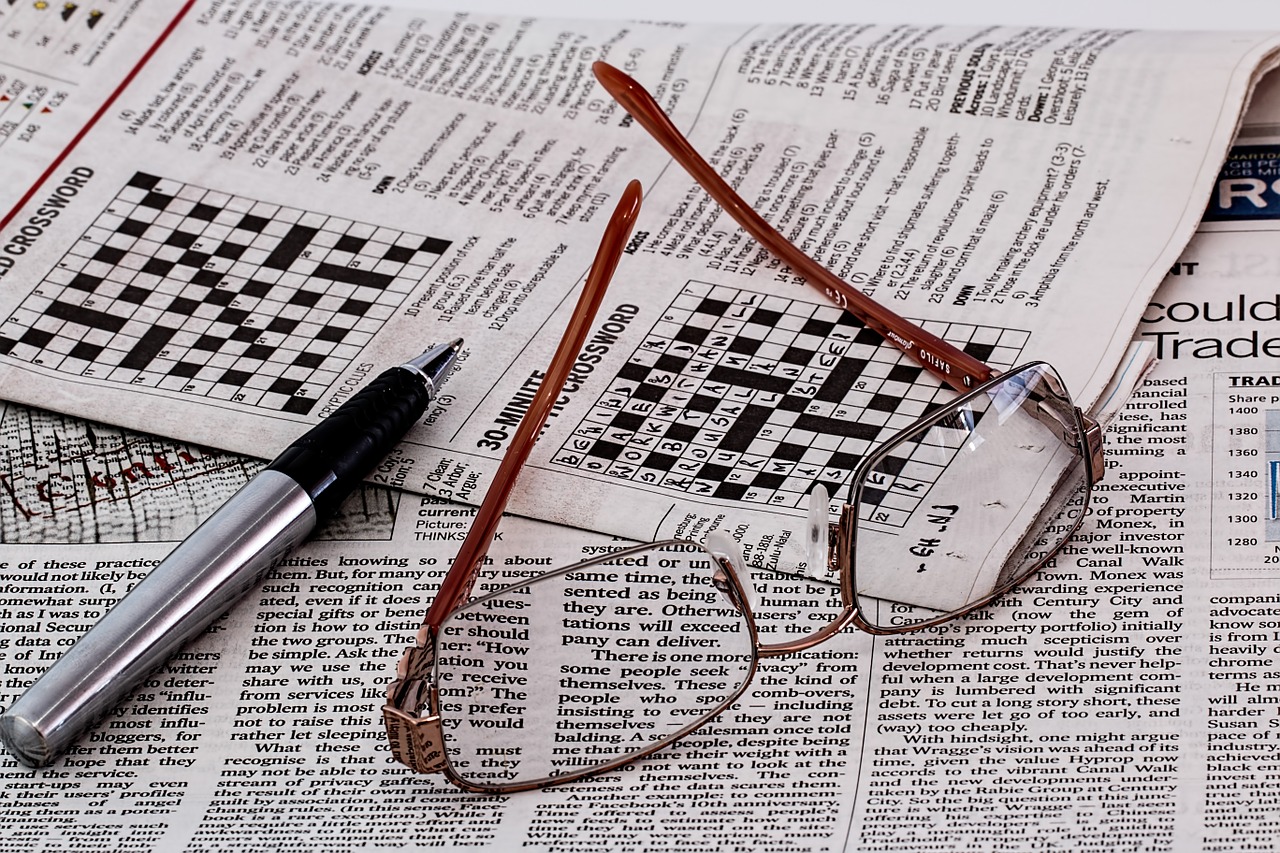 newspaper puzzle, glasses and pencil