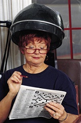 lady under a hairdryer solving a crossword puzzle